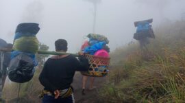 Para porter sedang membawa barang-barang pendaki menuju Gunung Rinjani